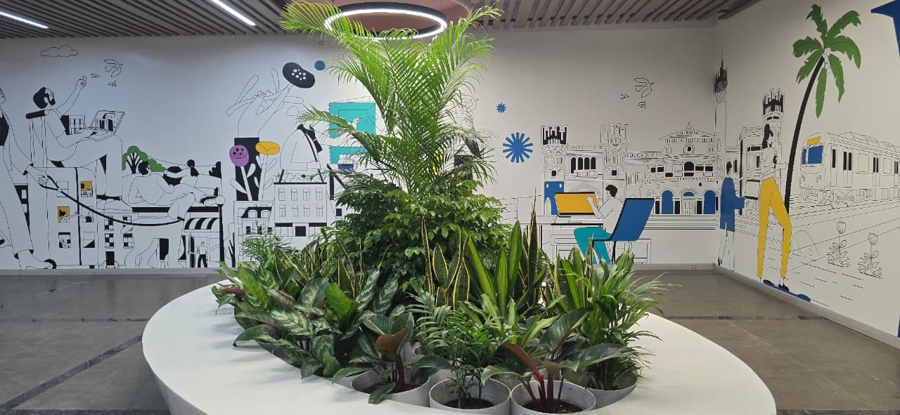 Circular indoor plantscape island with a tall palm, snake plants and a ring light
