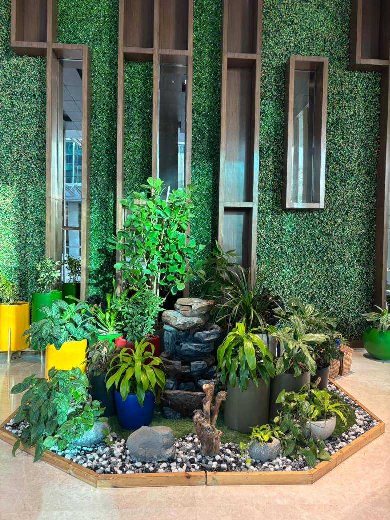 Indoor plant island with a stone water fountain, river stones and a living wall