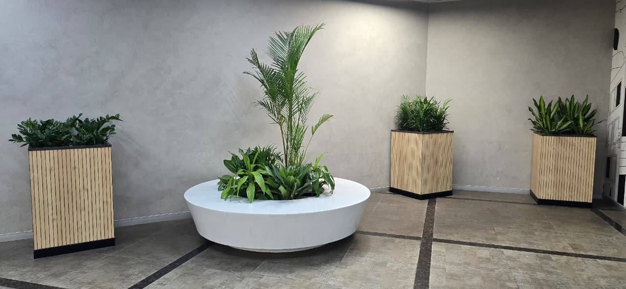 Minimalist office corner with a circular planter and wood-slat planters